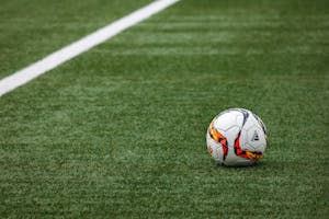 Ein leuchtender Fußball liegt auf einem makellosen Rasen neben einer weißen Seitenlinie.