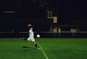 Dynamische Actionaufnahme eines Fußballspielers, der während eines Nachtmatches in Somerset, England, den Ball schießt.